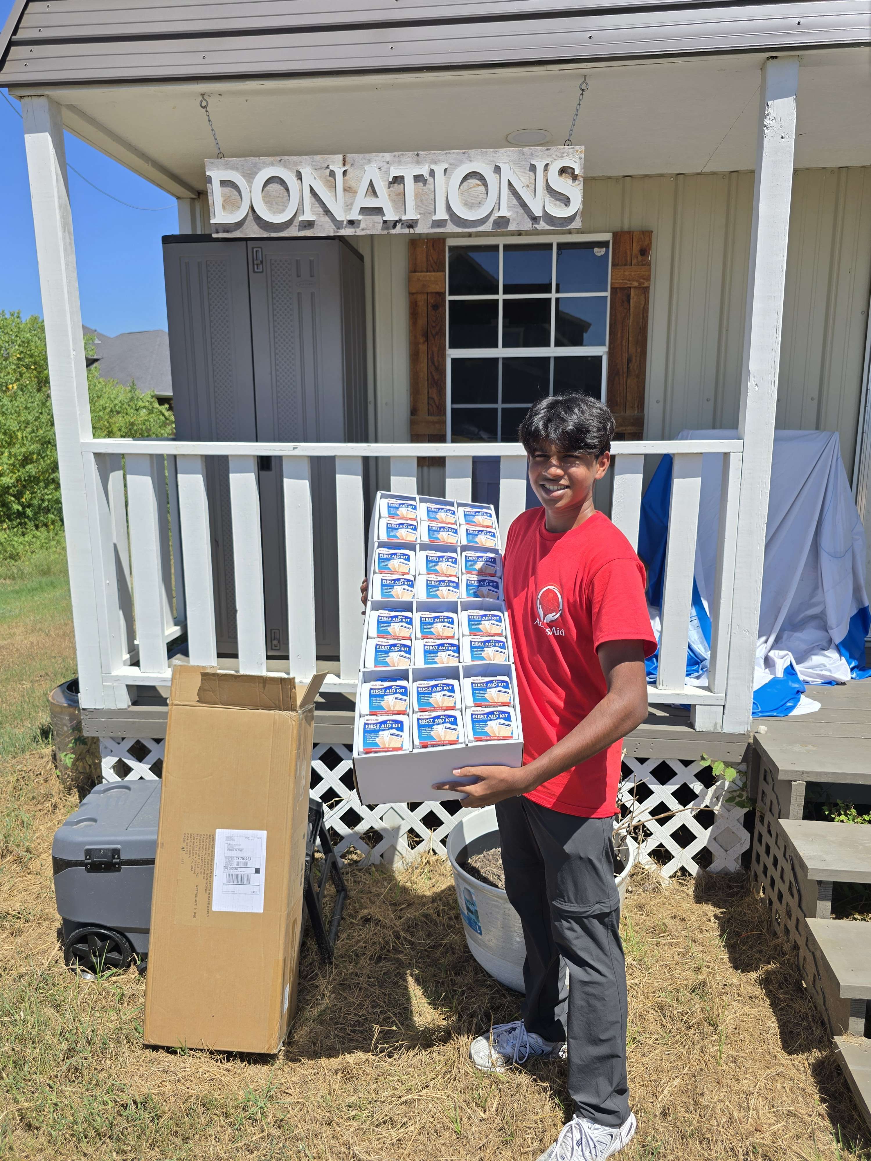 AccessAid volunteer with a box of first-aid kits at Abba's House