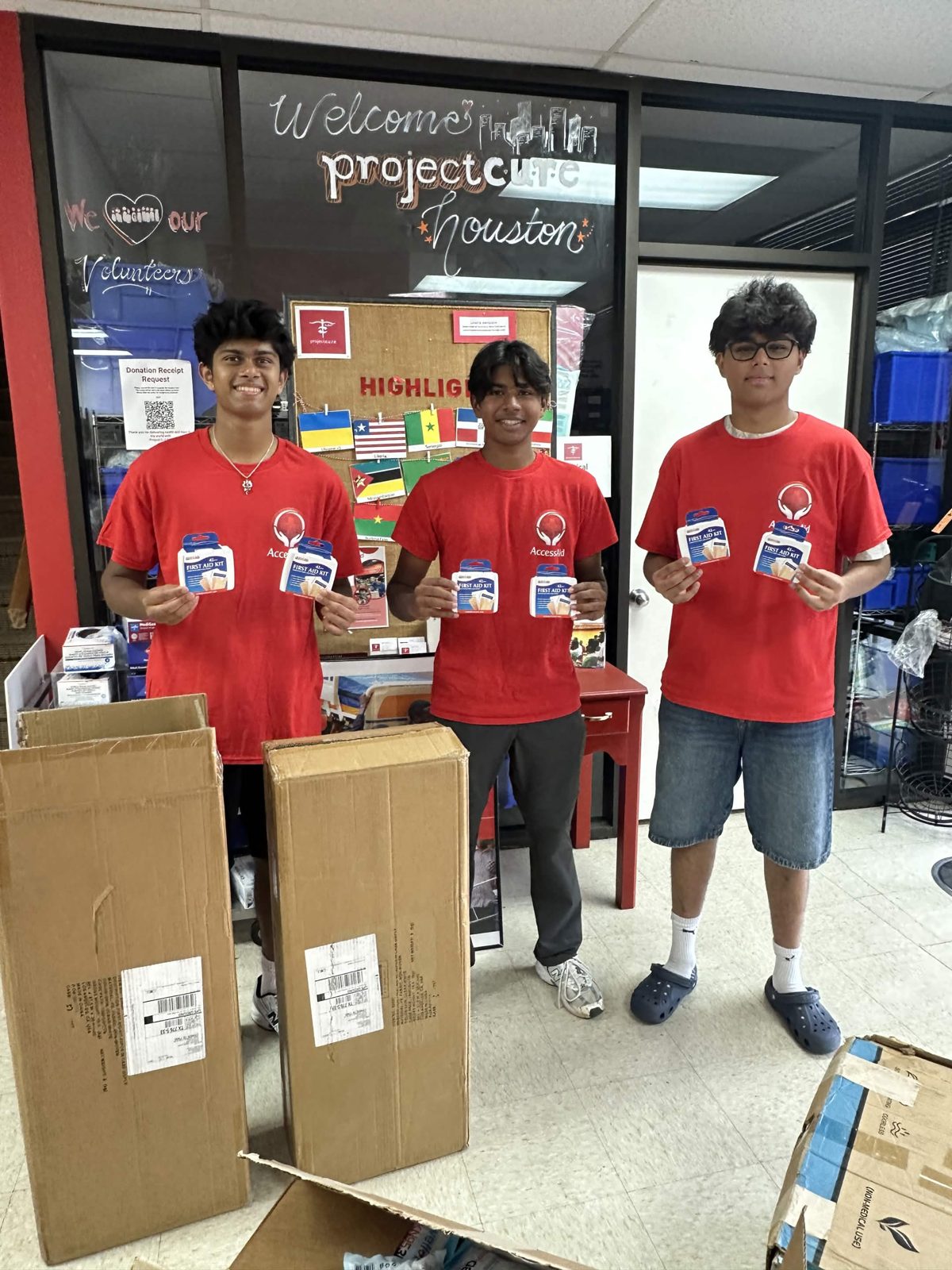 Three AccessAid volunteers holding first-aid kits at Project C.U.R.E. Houston